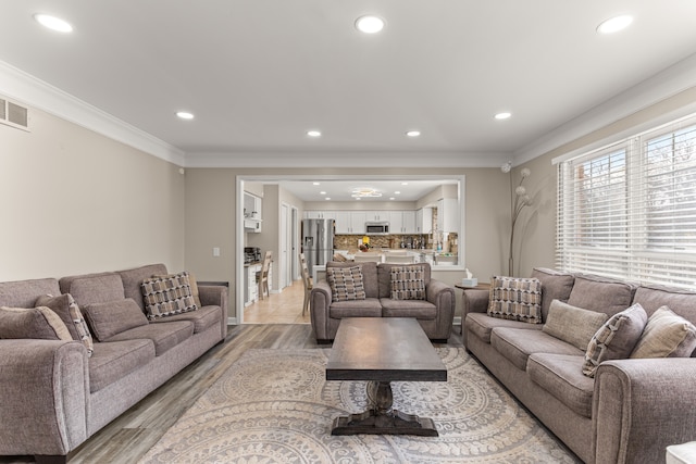 living room with crown molding and light hardwood / wood-style flooring