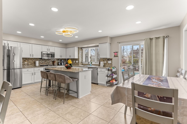 kitchen featuring white cabinets, light stone countertops, a kitchen island, and stainless steel appliances