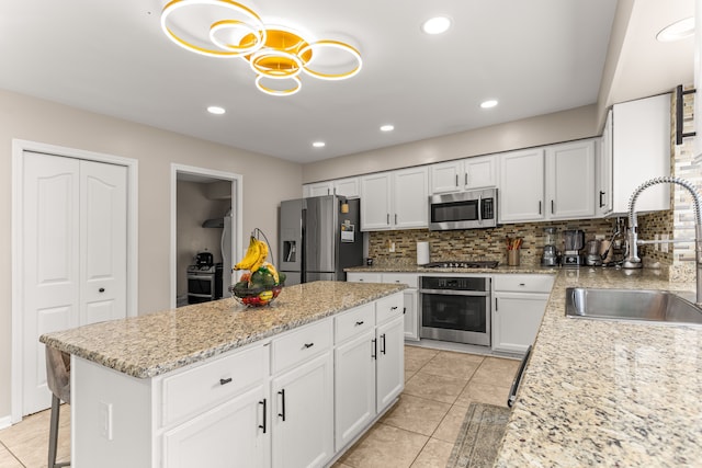 kitchen with white cabinetry, sink, stainless steel appliances, tasteful backsplash, and decorative light fixtures