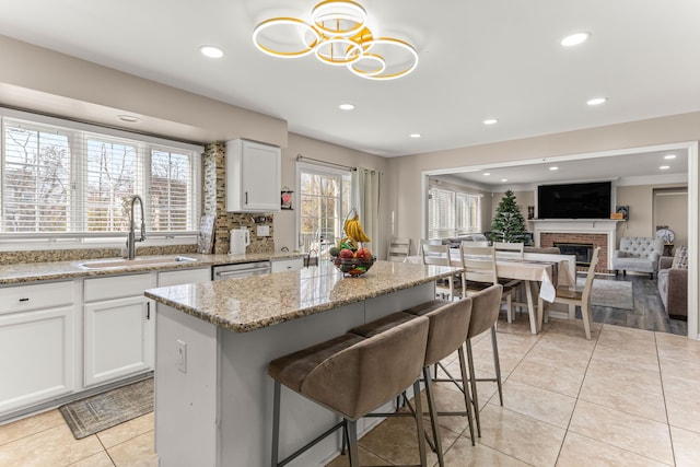 kitchen featuring a center island, light stone countertops, white cabinetry, and sink