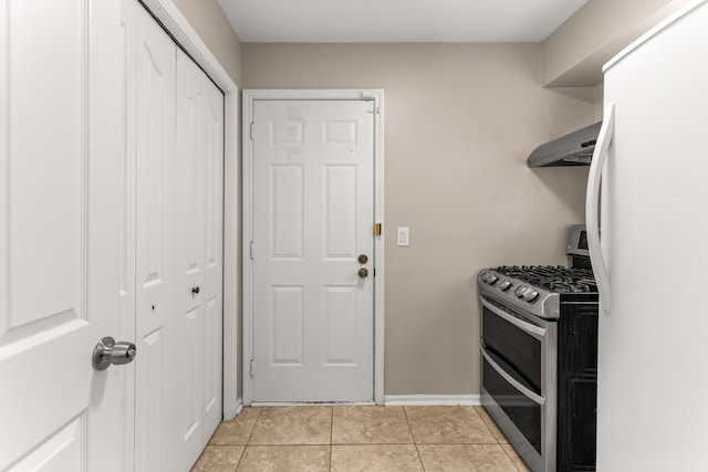 kitchen featuring white refrigerator, range with two ovens, light tile patterned floors, and exhaust hood