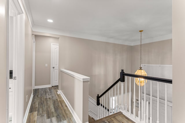 hallway featuring hardwood / wood-style flooring, an inviting chandelier, and crown molding