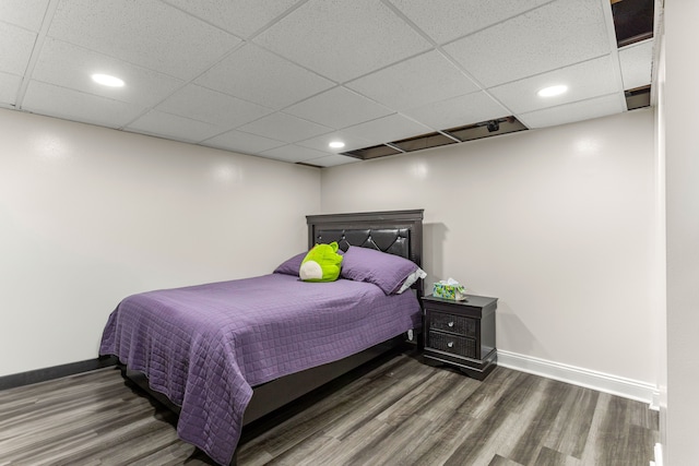 bedroom with a paneled ceiling and dark hardwood / wood-style flooring