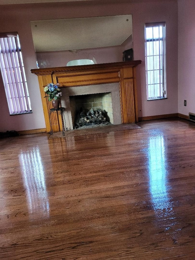 unfurnished living room with a tile fireplace and dark wood-type flooring