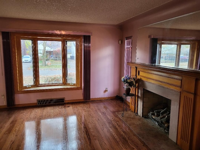 unfurnished living room featuring hardwood / wood-style floors and a textured ceiling