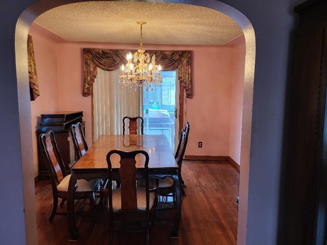 dining area with a textured ceiling, dark wood-type flooring, and a notable chandelier