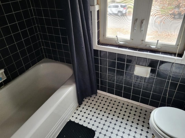 bathroom featuring shower / bath combo, toilet, and tile walls