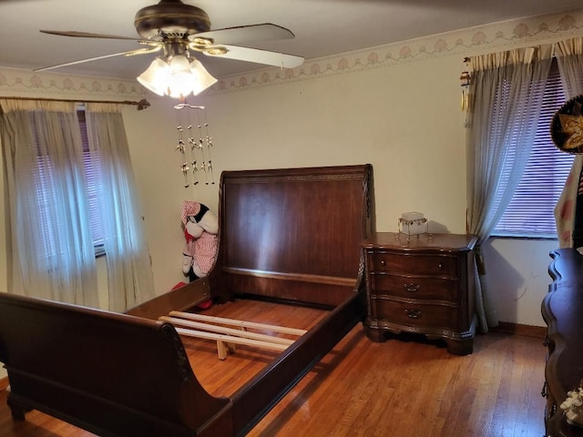 bedroom with multiple windows, hardwood / wood-style floors, ceiling fan, and ornamental molding