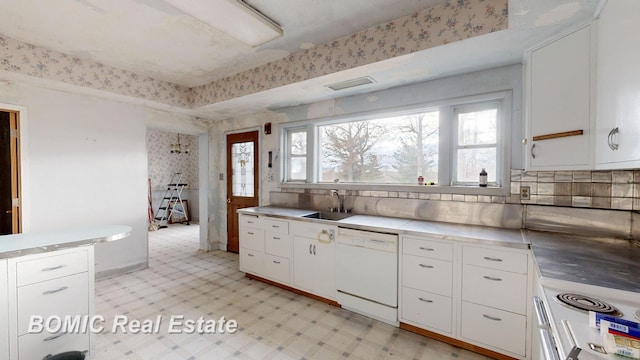 kitchen with tasteful backsplash, white appliances, stainless steel counters, sink, and white cabinetry