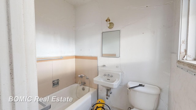 bathroom with sink, toilet, a bath, and tile walls