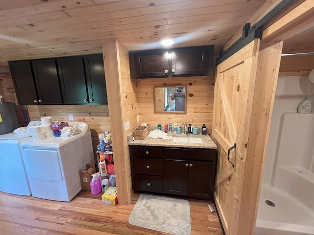 washroom featuring wooden walls, a barn door, light wood-type flooring, separate washer and dryer, and wood ceiling