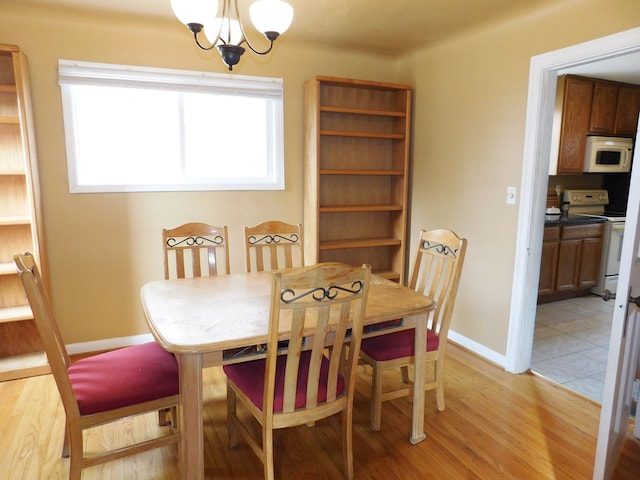 dining space with a wealth of natural light, a notable chandelier, and light wood-type flooring