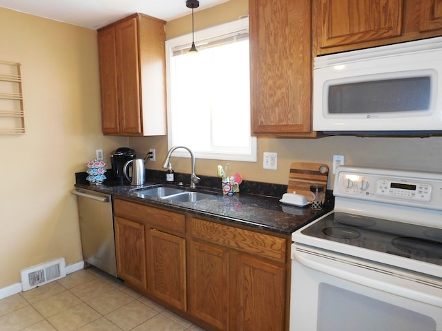 kitchen with pendant lighting, sink, white appliances, light tile patterned floors, and dark stone counters