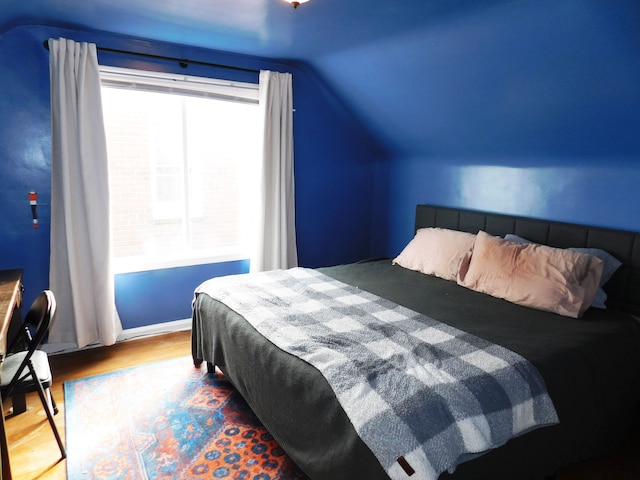 bedroom with vaulted ceiling and wood-type flooring