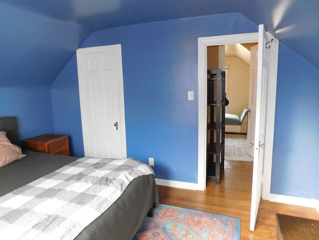 bedroom with wood-type flooring and vaulted ceiling