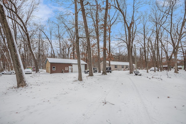 yard covered in snow featuring a garage and an outdoor structure