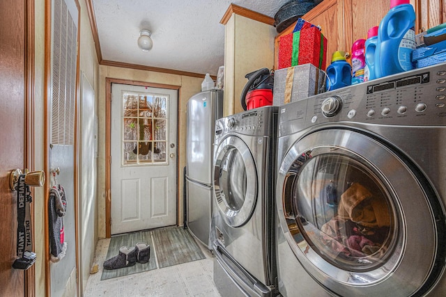 washroom with cabinets, a textured ceiling, crown molding, and washing machine and clothes dryer