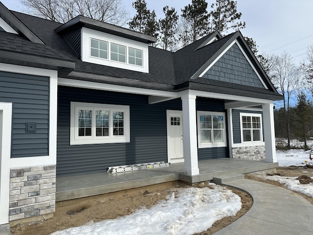 snow covered property entrance with covered porch