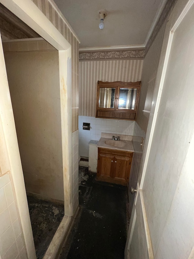 bathroom with crown molding, vanity, and tile walls