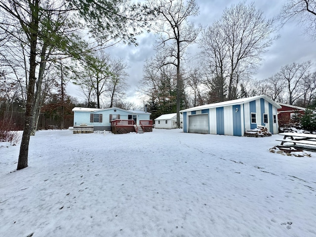 yard layered in snow with an outdoor structure, a garage, and a deck