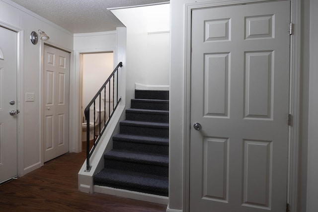 staircase with hardwood / wood-style floors and a textured ceiling