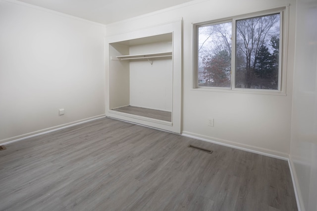 unfurnished bedroom with hardwood / wood-style flooring, ornamental molding, and a closet