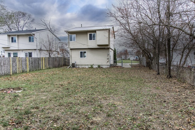 rear view of property featuring central AC unit and a lawn