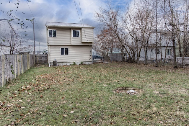 back of house with central air condition unit and a lawn