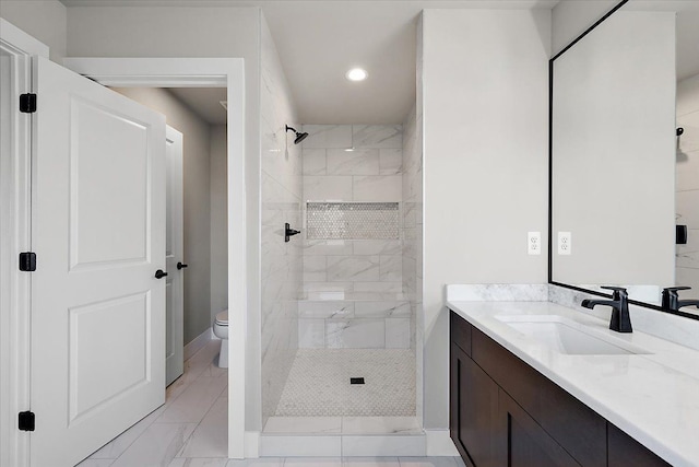 bathroom featuring tiled shower, vanity, and toilet