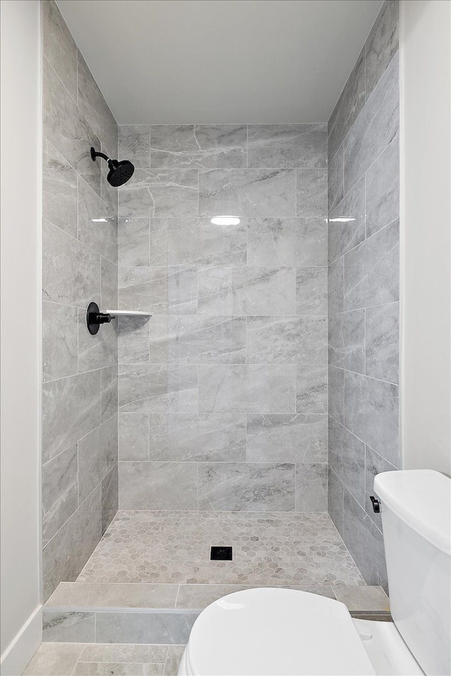 bathroom featuring toilet and a tile shower