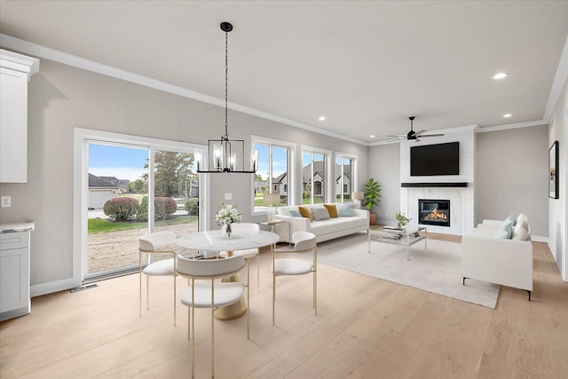 dining area with crown molding, light hardwood / wood-style floors, a fireplace, and plenty of natural light