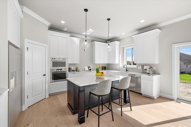 kitchen featuring white cabinets, a center island, decorative light fixtures, stainless steel appliances, and crown molding