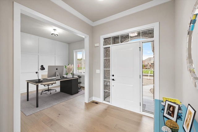 entryway with light hardwood / wood-style flooring and crown molding