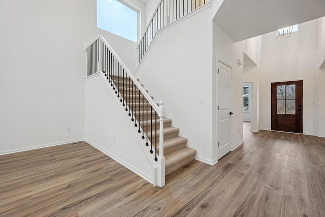 entryway with light wood-type flooring, a towering ceiling, plenty of natural light, and a notable chandelier