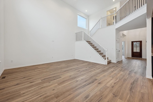 unfurnished living room with a towering ceiling and light hardwood / wood-style floors