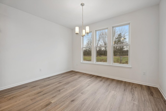 unfurnished dining area with a chandelier and light hardwood / wood-style flooring