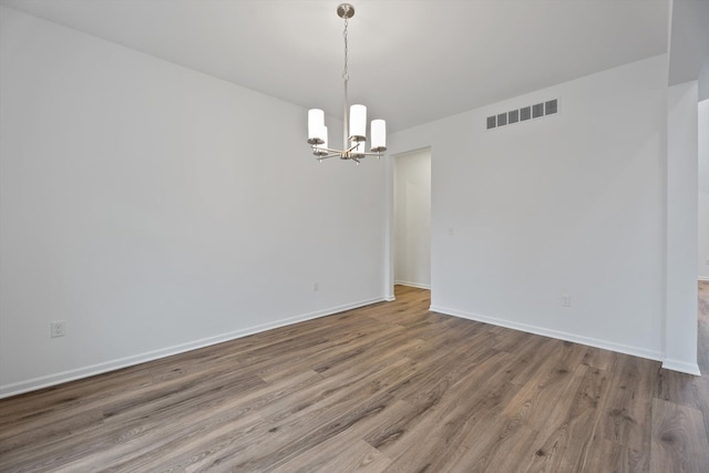 empty room with a chandelier and hardwood / wood-style flooring