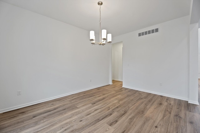 spare room featuring hardwood / wood-style floors and a chandelier