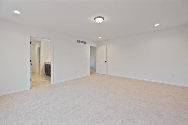 unfurnished bedroom featuring light carpet and connected bathroom