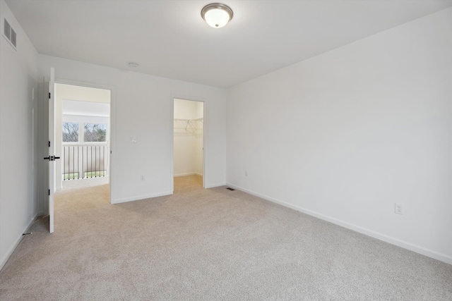 unfurnished bedroom with a walk in closet, light carpet, and a closet