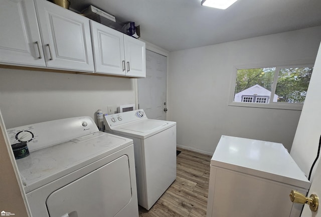 laundry area featuring washer and clothes dryer, cabinets, and light hardwood / wood-style flooring