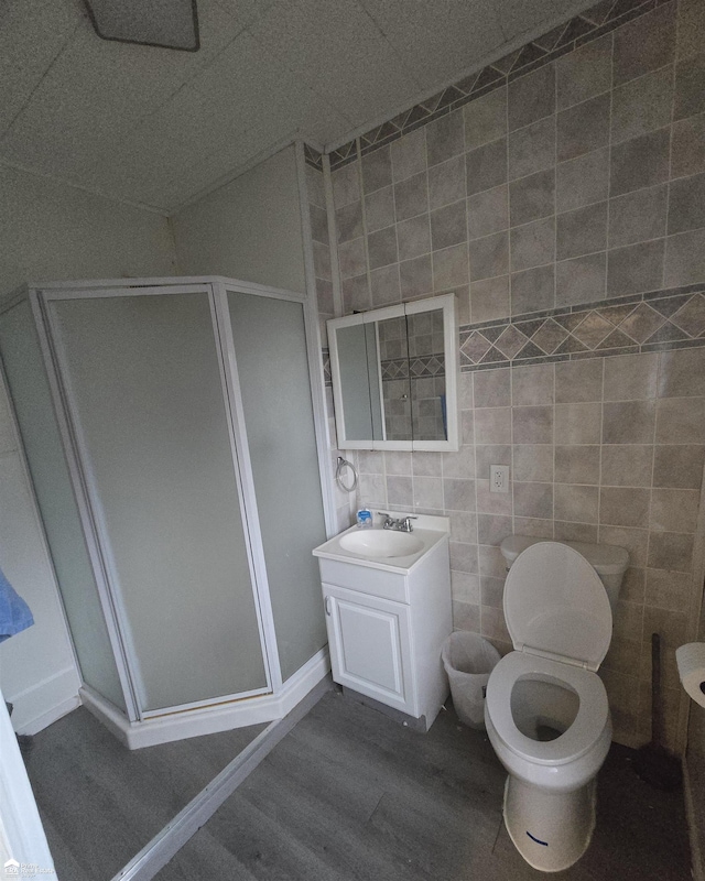 bathroom featuring vanity, wood-type flooring, walk in shower, and tile walls