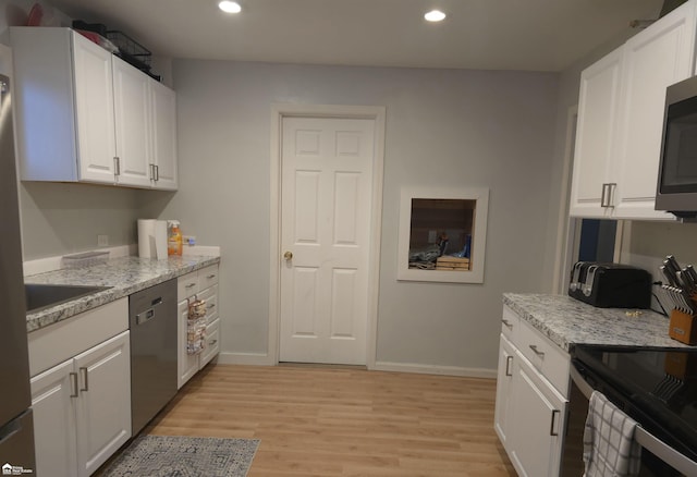 kitchen featuring light stone counters, stainless steel appliances, sink, white cabinets, and light hardwood / wood-style floors