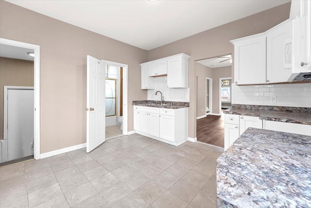 kitchen with sink, backsplash, white cabinetry, and dark stone countertops