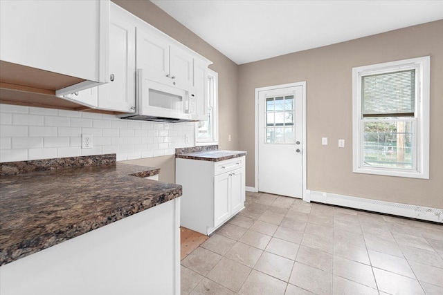 kitchen with tasteful backsplash, white cabinetry, dark stone counters, and light tile patterned flooring