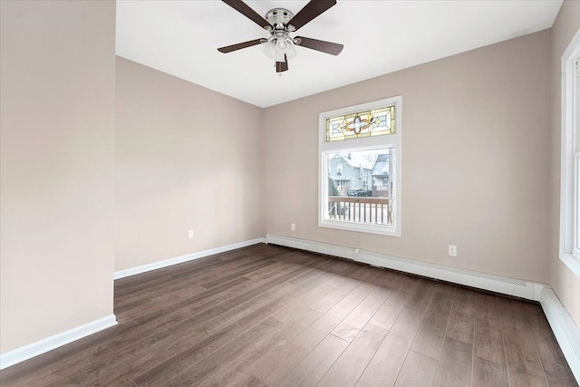 empty room with dark hardwood / wood-style flooring, baseboard heating, and ceiling fan