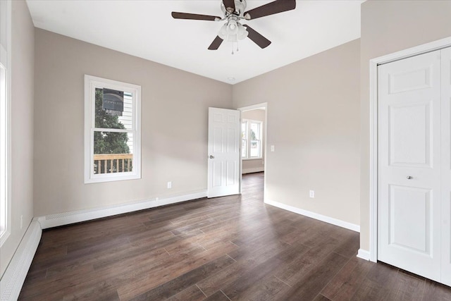 unfurnished bedroom featuring dark hardwood / wood-style flooring, a closet, ceiling fan, and a baseboard heating unit