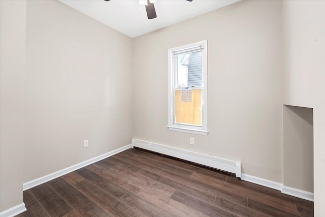 empty room featuring baseboard heating, ceiling fan, and dark wood-type flooring