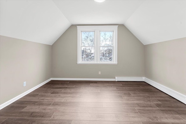 additional living space featuring vaulted ceiling, a baseboard radiator, and dark hardwood / wood-style floors