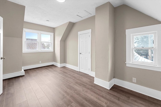 bonus room featuring hardwood / wood-style floors, a textured ceiling, and lofted ceiling